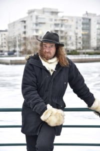 Muusikko Teho Majamäki FinFamin Labyrintti_lehdessä nojaa aitaan lumisessa maisemassa_kuva Marika Finne